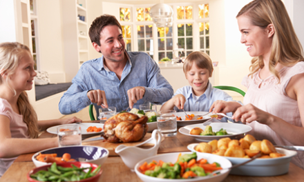 family having roast chicken dinner at table