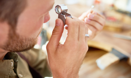 man in pawnshop examines item with magnifying glass