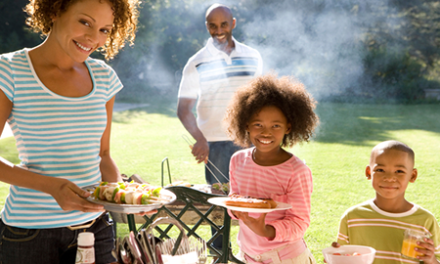 smiling family of four at outdoor barbecue